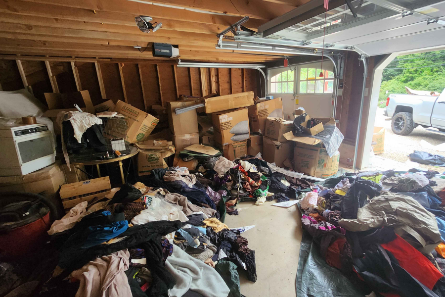 Cluttered garage filled with boxes, clothes, and stored items before an Anchorline cleanout in Fairfield County