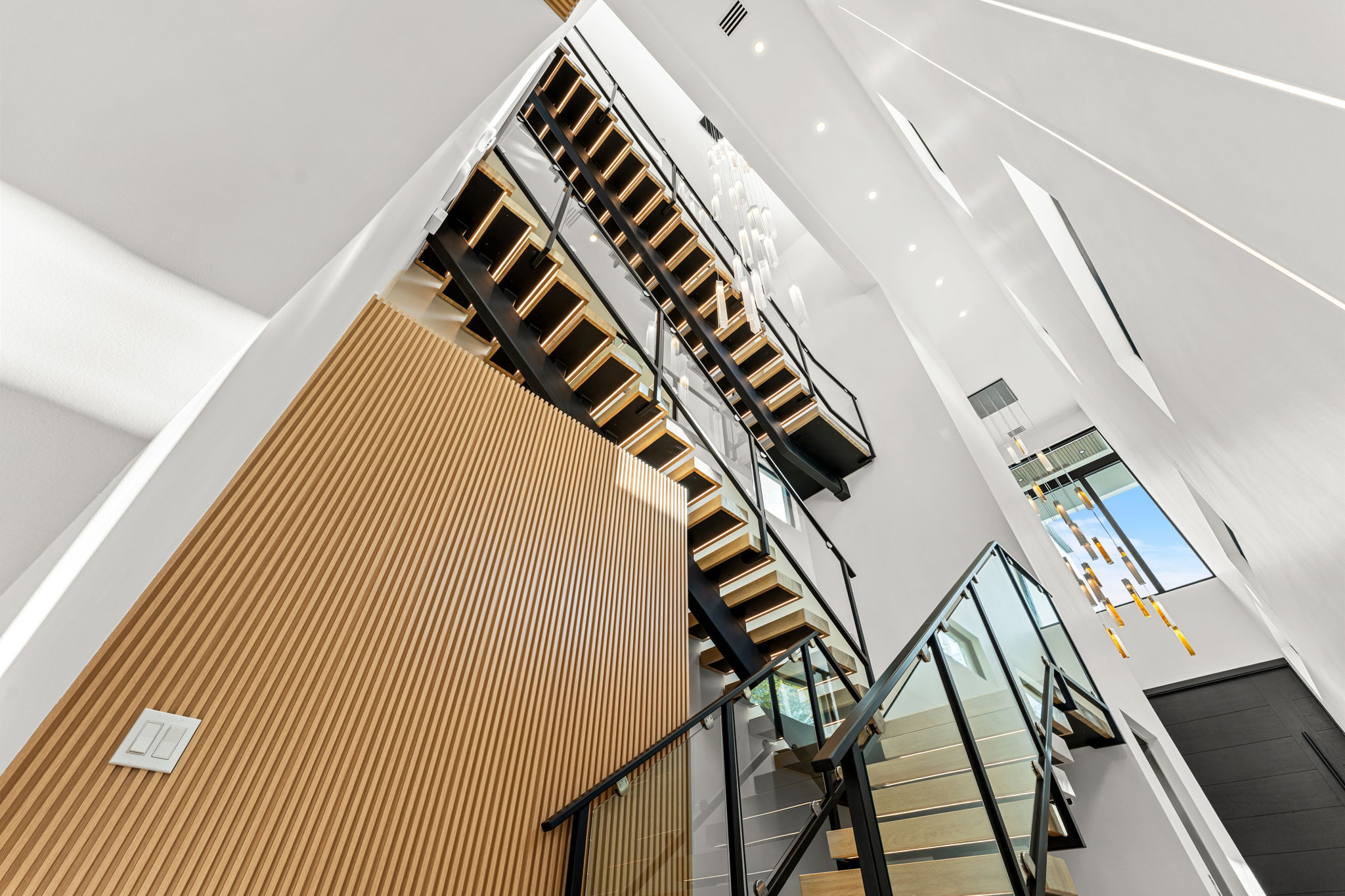 Architectural modern open staircase with slatted wood wall and vertical lighting