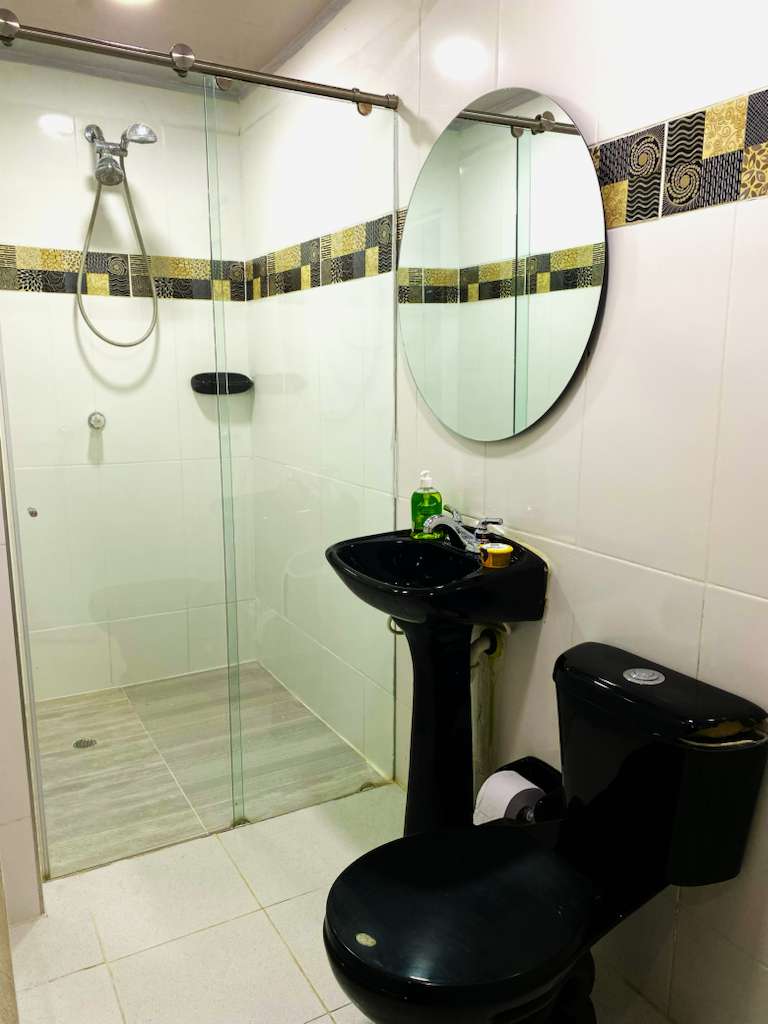 Baño moderno con espejo circular y acabados elegantes