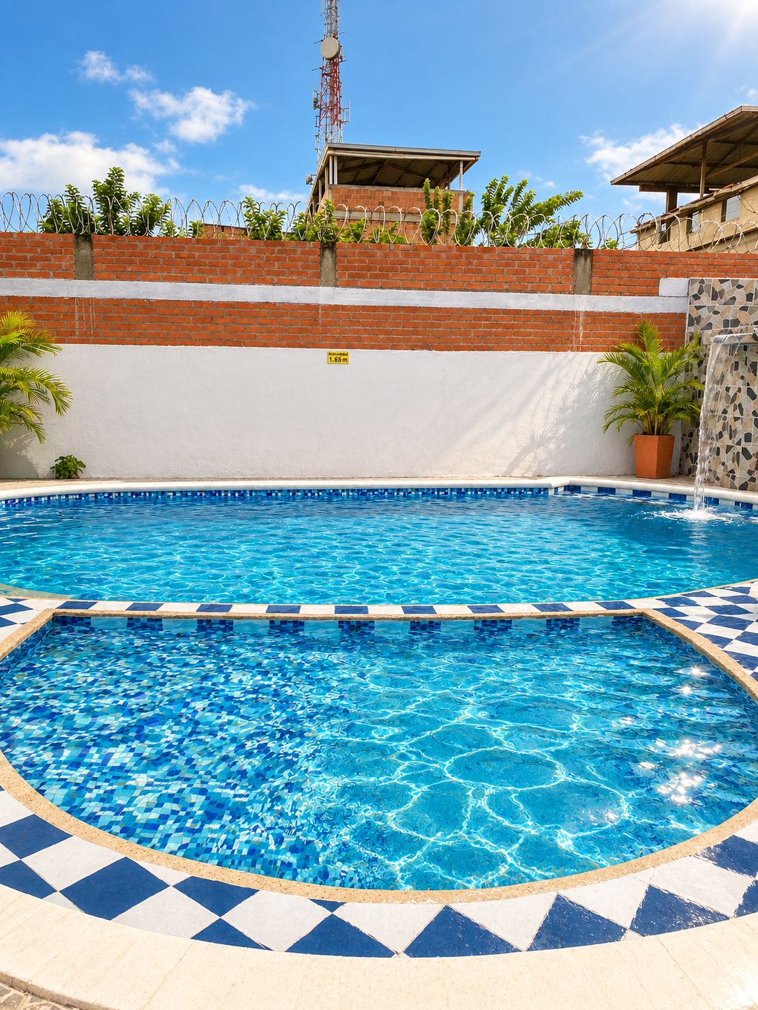 Piscina con zona de niños y muro de piedra con fuente