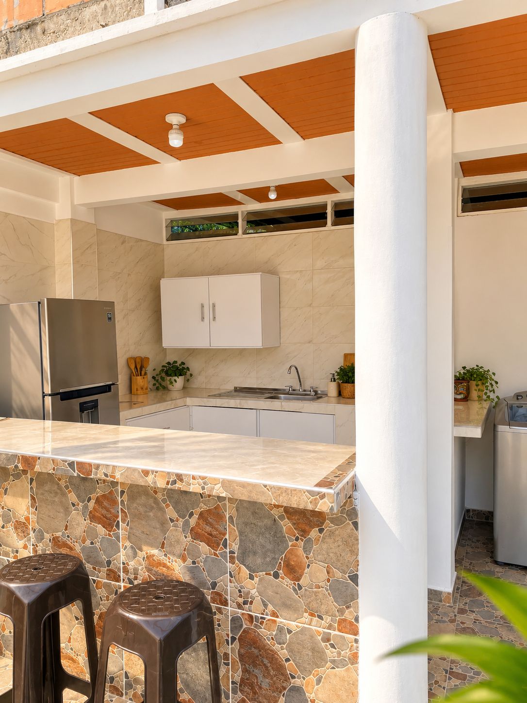 Cocina abierta con barra americana y acabados en piedra de El Parce Rozo