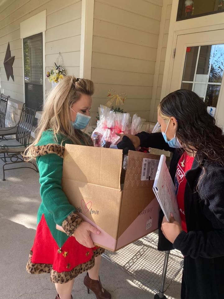 Volunteers carrying boxes filled with Adopt a Senior gift bags up to a community home entrance