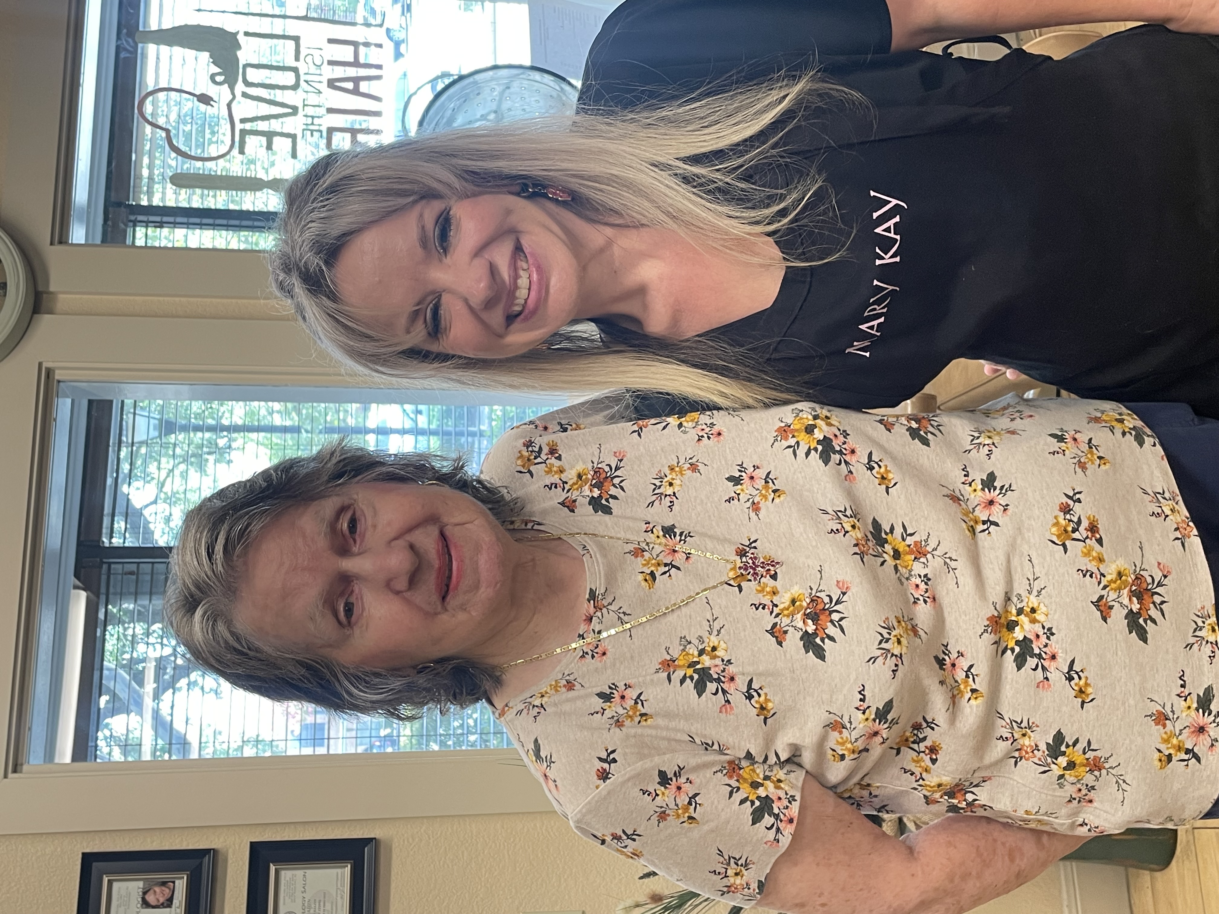 A senior resident smiling happily alongside Theresa during a pampering makeover day