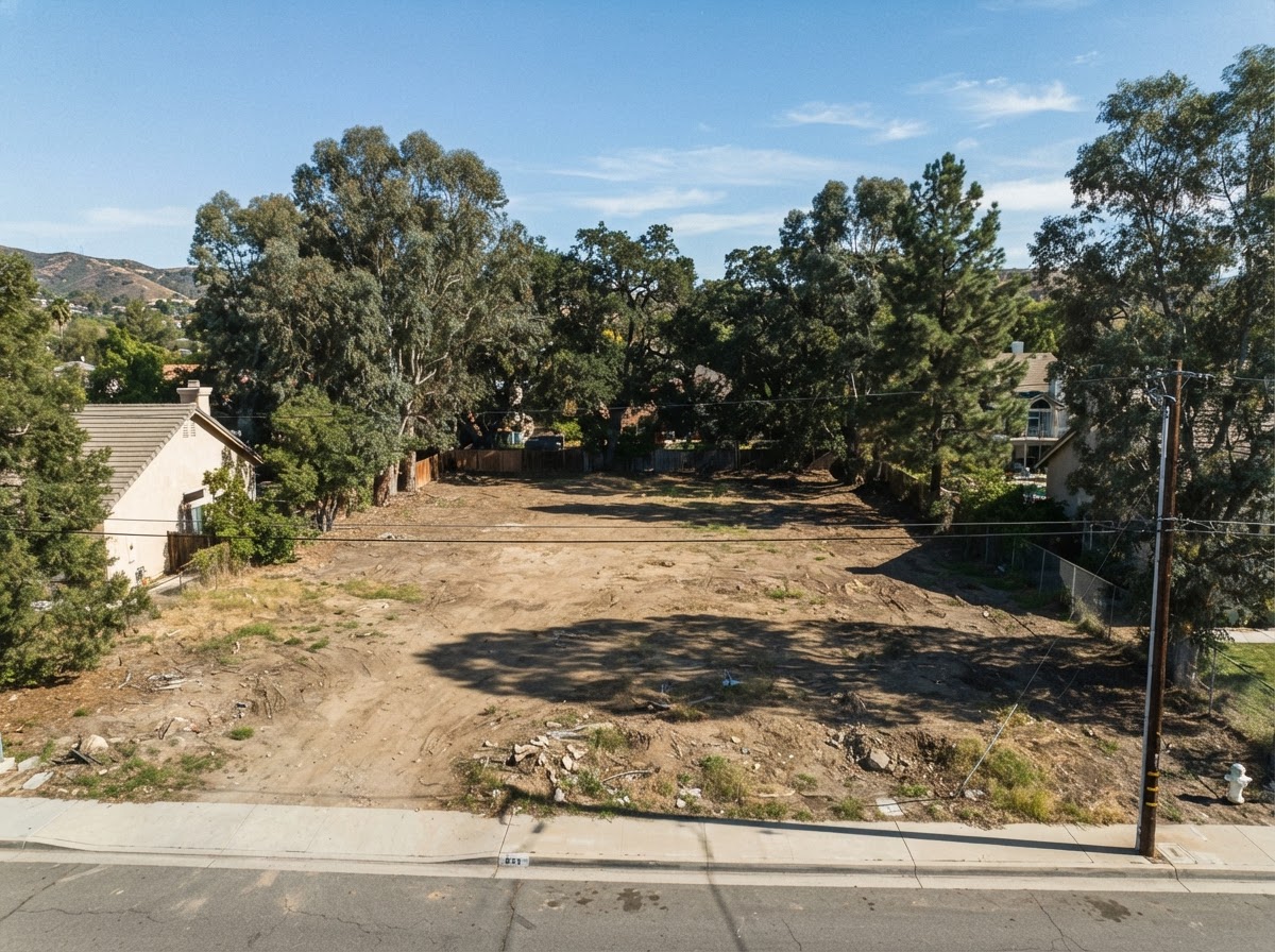 A cleared residential lot with mature trees remaining at the edges.