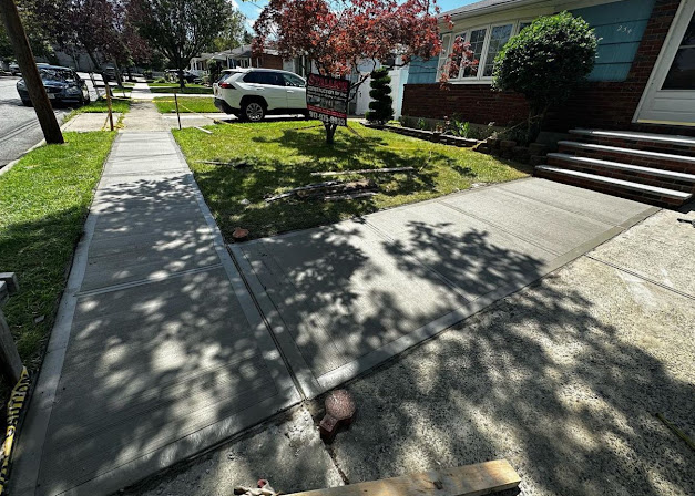 Freshly poured concrete walkway and front steps with lawn