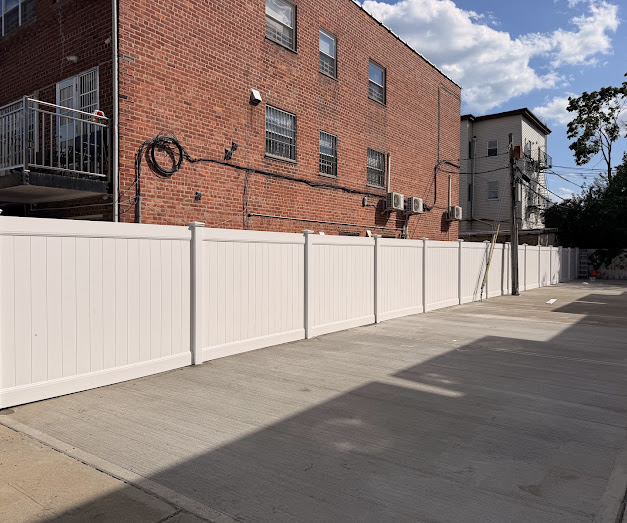 Concrete parking area with vinyl fencing on residential property