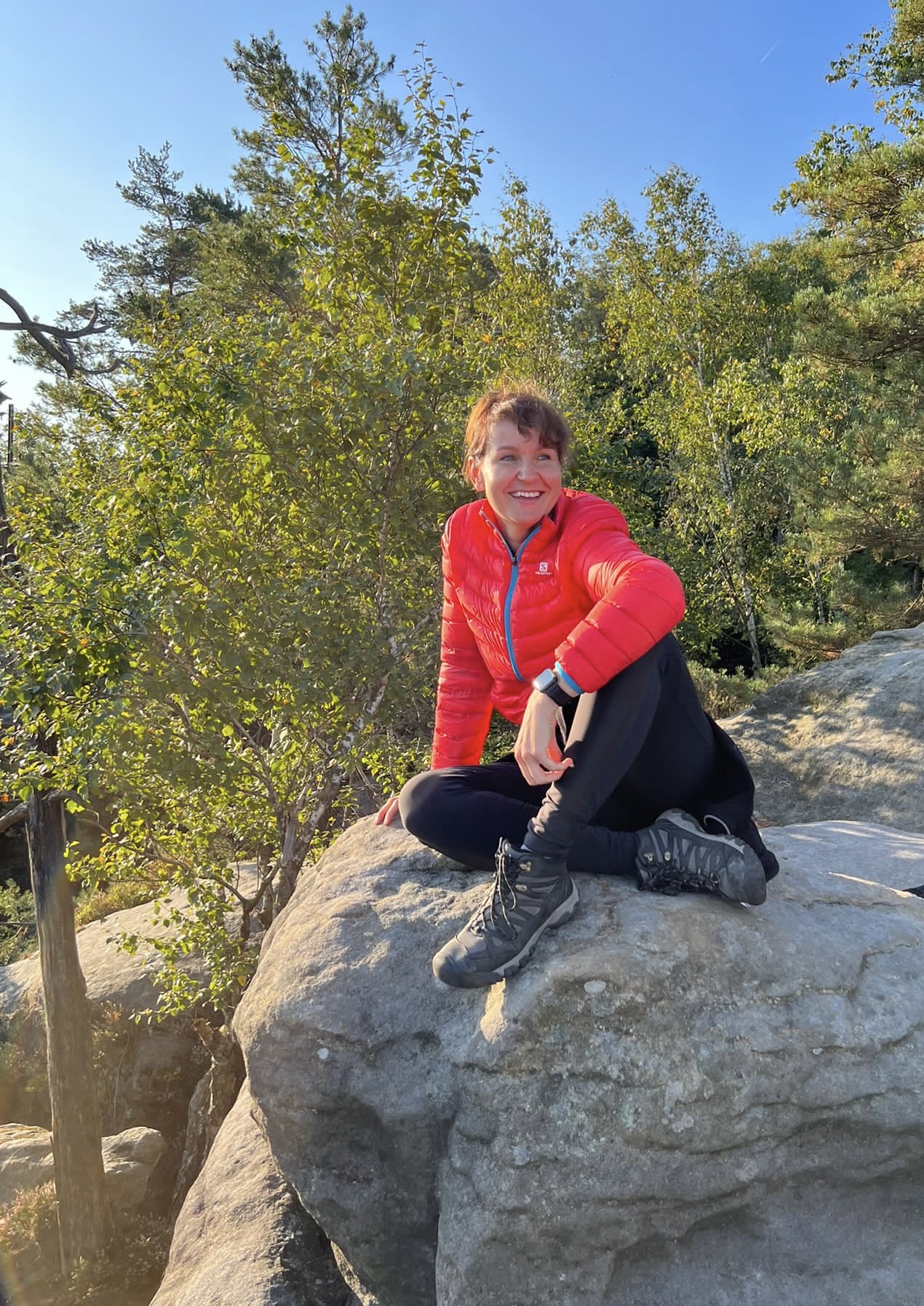 Anja Kräher lacht entspannt auf einem Felsen in der sächsischen Natur