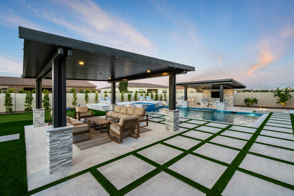 Real Scottsdale backyard at golden hour with a pool, travertine deck, and stone outdoor kitchen