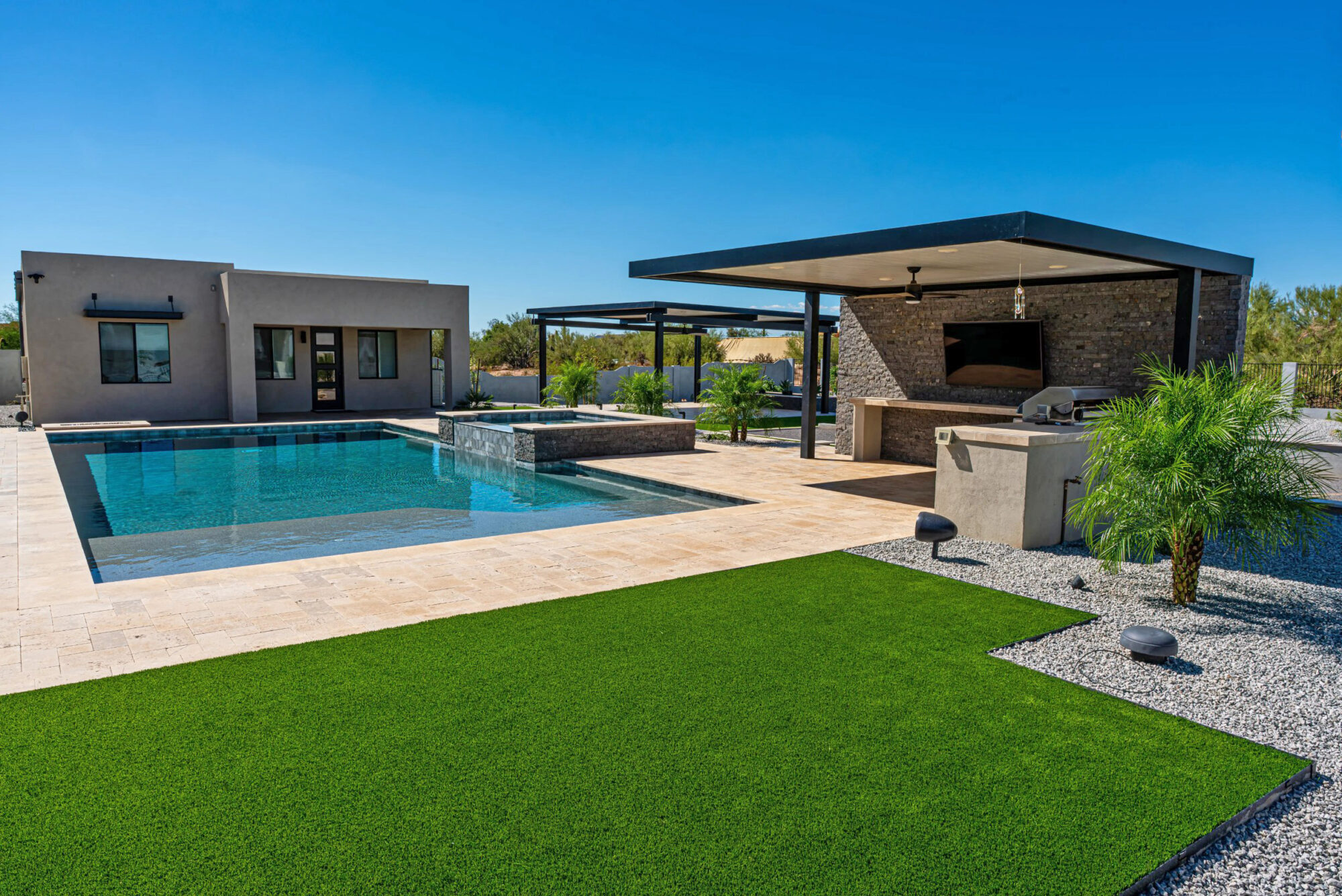Backyard transformation with swimming pool, raised spa, modern covered outdoor kitchen, and turf