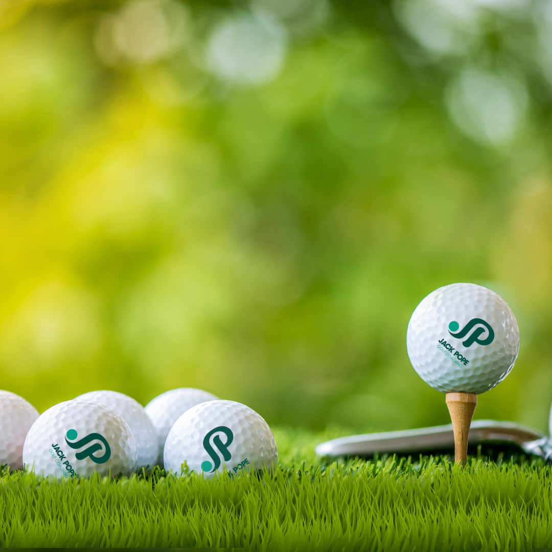 Jack Pope Golf branded golf balls lined up on fresh green grass with tee and iron
