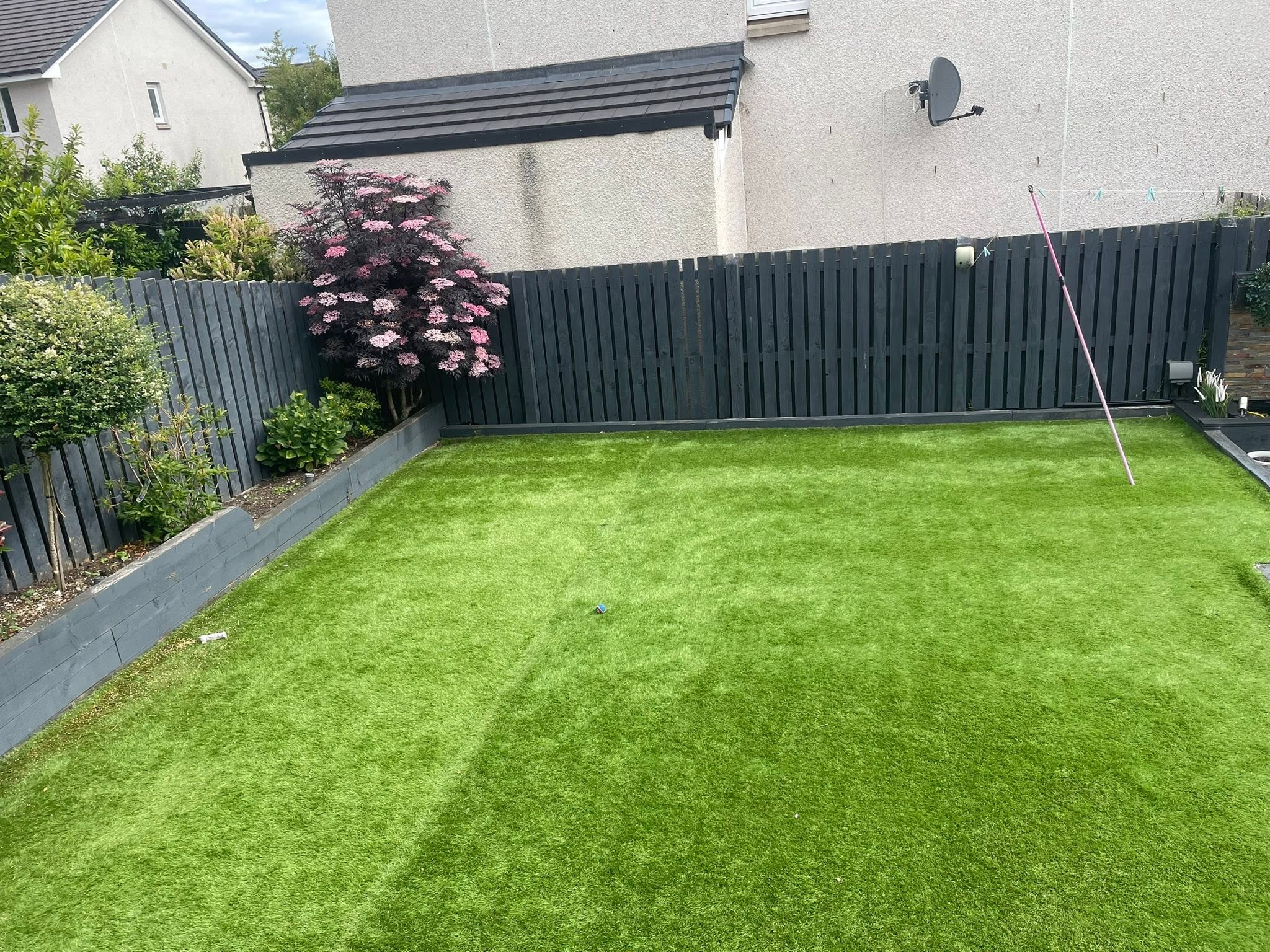 Pristine lawn installation with painted boundary fence and raised planters by Emerald Edge Landscaping Services in Dalkeith