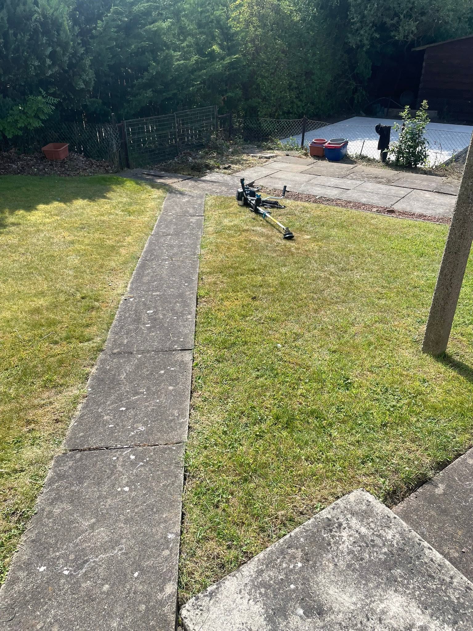 Garden maintenance and lawn strimming along paved stepping path