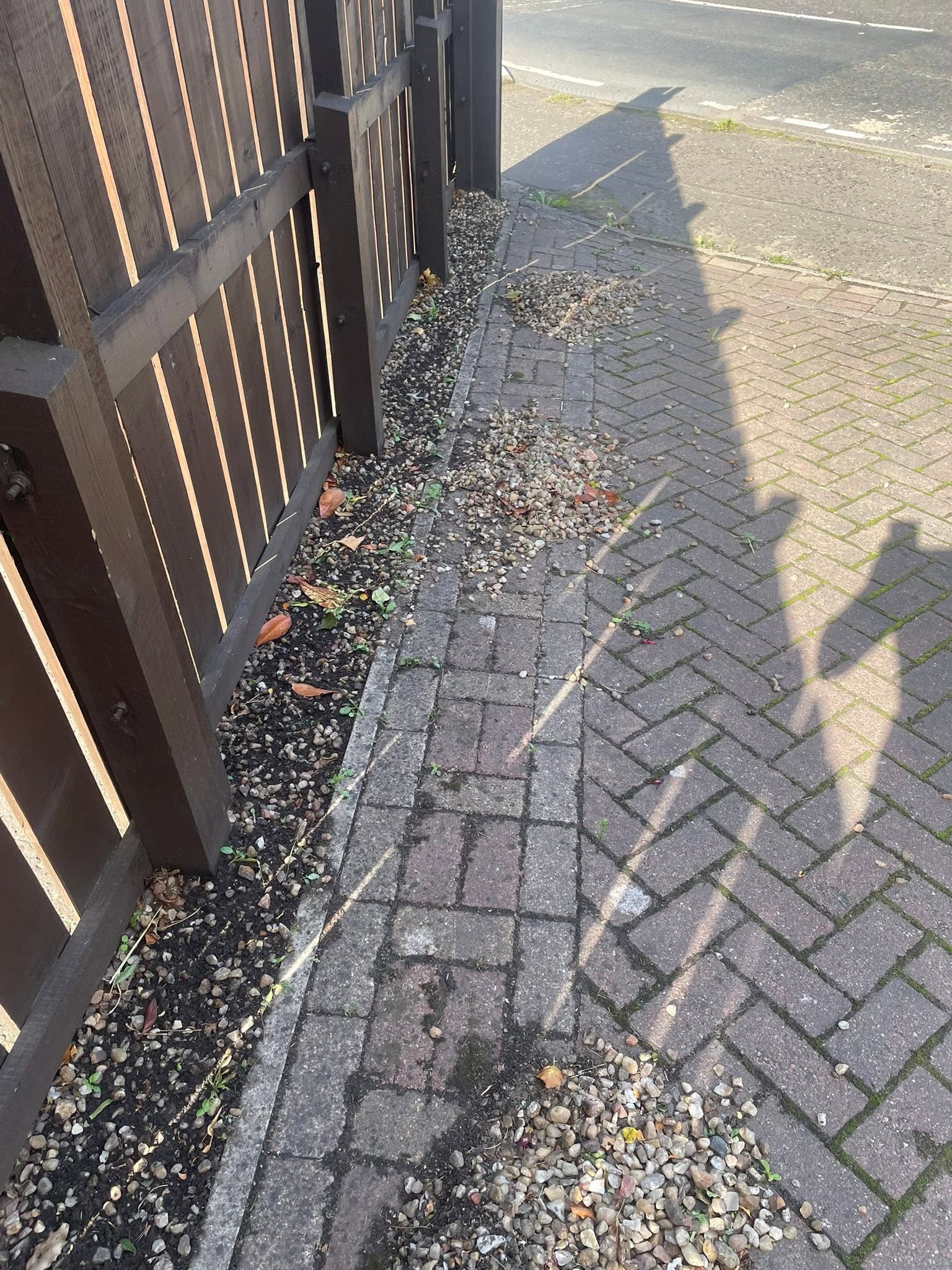 Border before: scattered loose gravel, weed growth and uneven edges alongside timber fence and block paving in Dalkeith