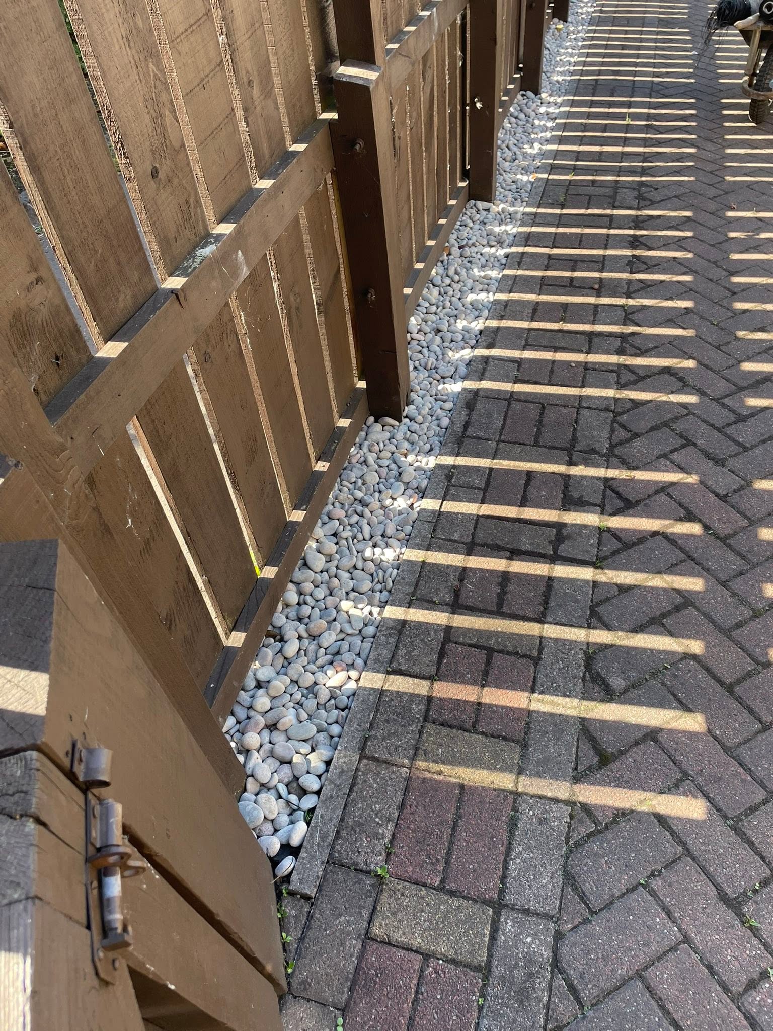 Border after: clean white decorative river pebbles neatly bordered along timber fence and power-washed block paving in Dalkeith