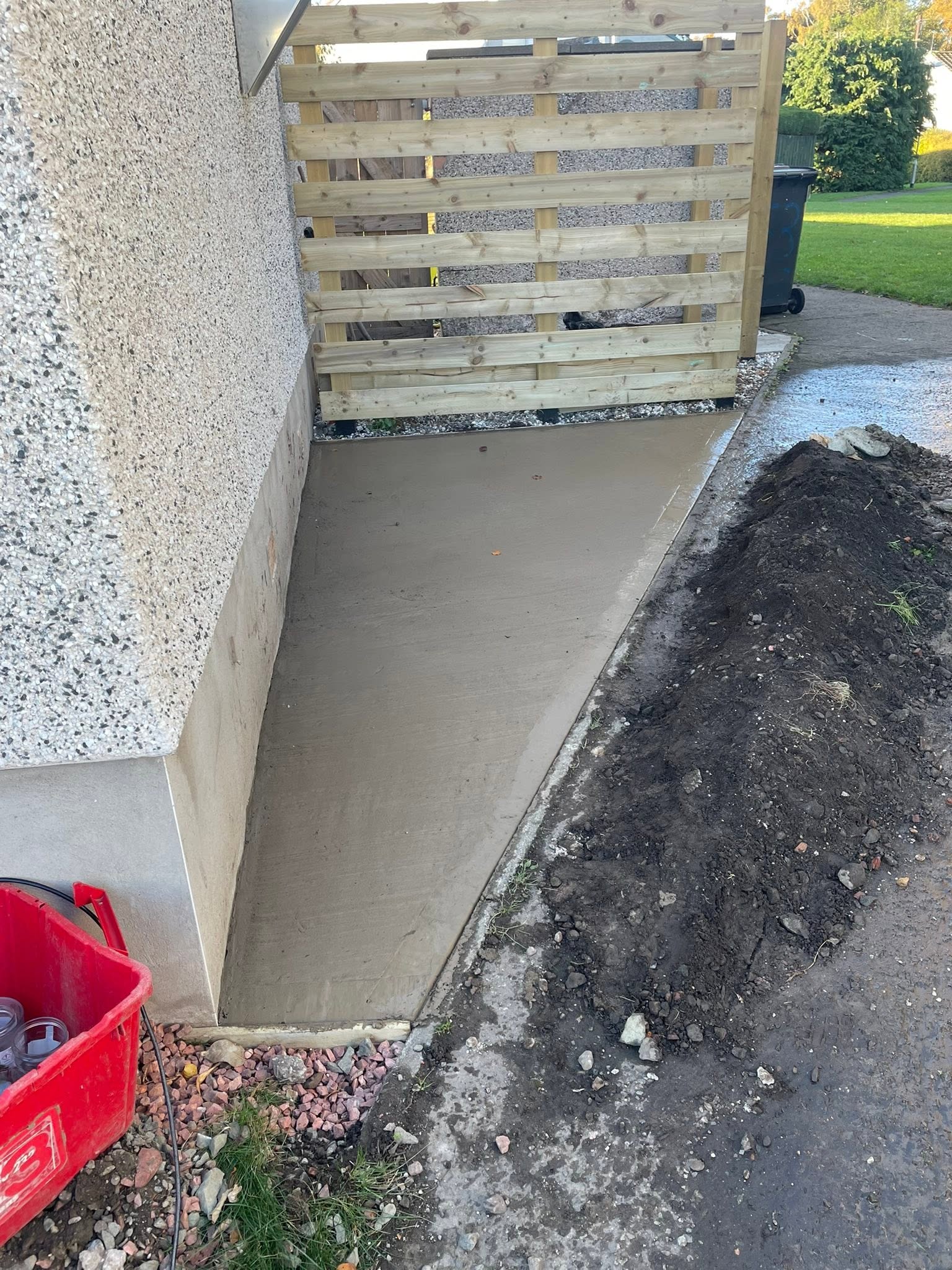 Freshly poured and finished smooth concrete base alongside timber screen fencing