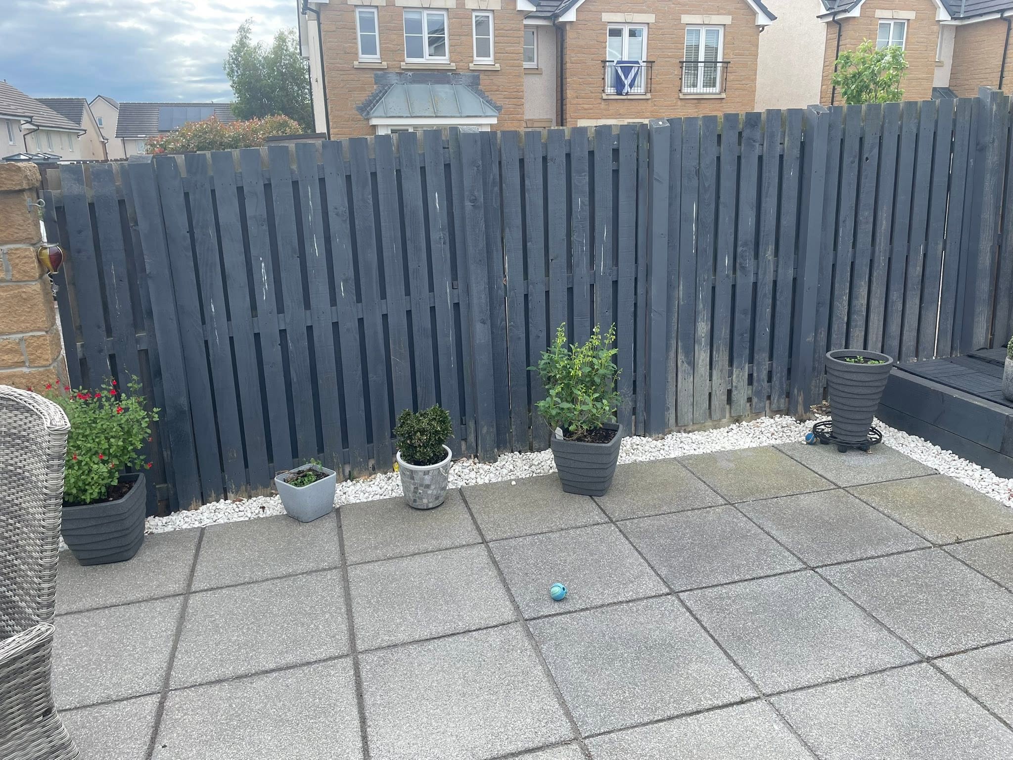 Paved patio area with grey boundary fencing and decorative stone borders by Emerald Edge Landscaping Services