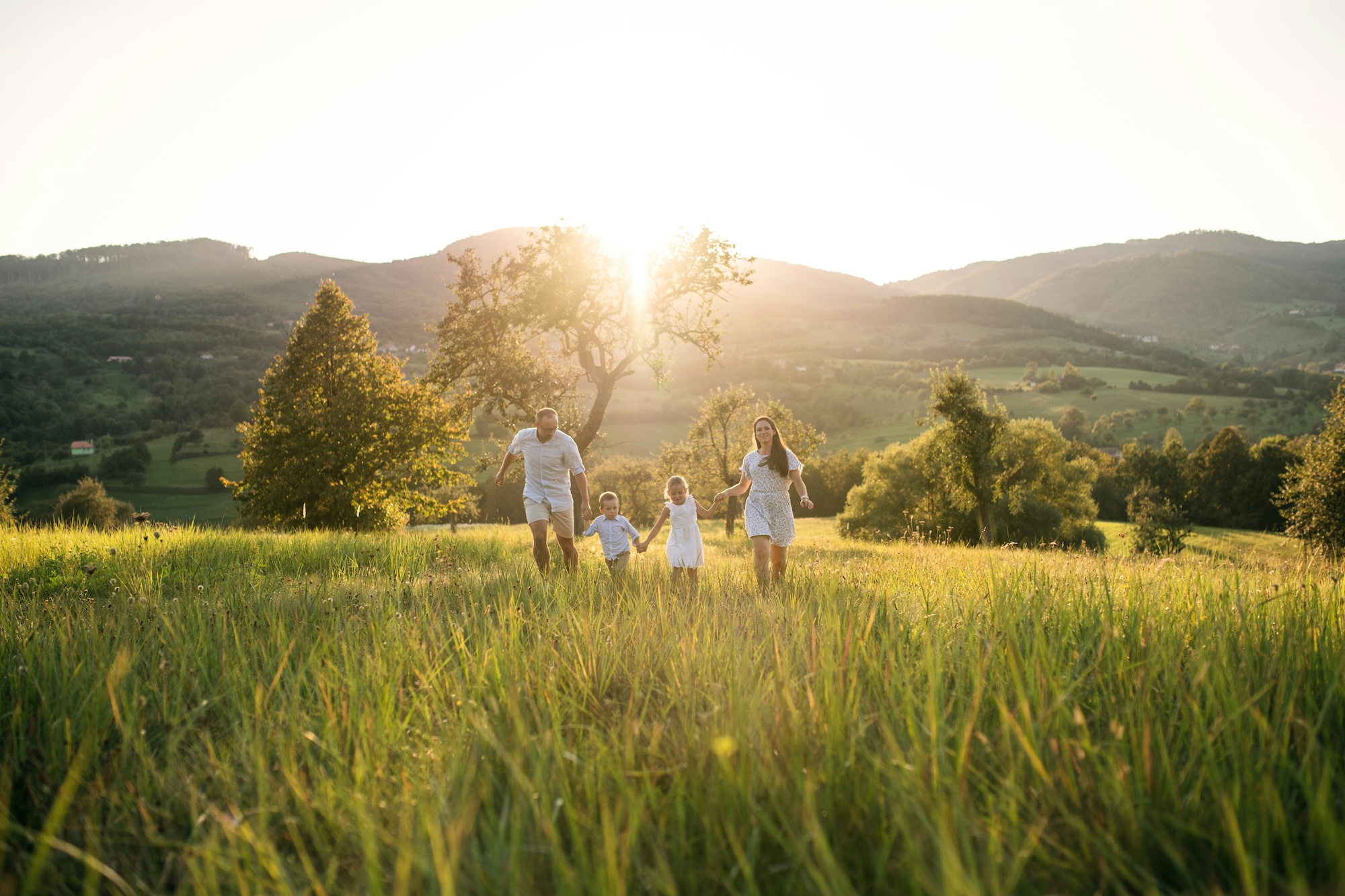 A family walking together through a sunlit countryside field at sunset