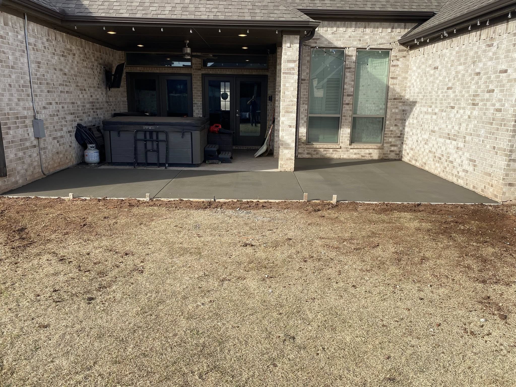 New concrete patio extension behind a brick home in Wichita Falls, TX