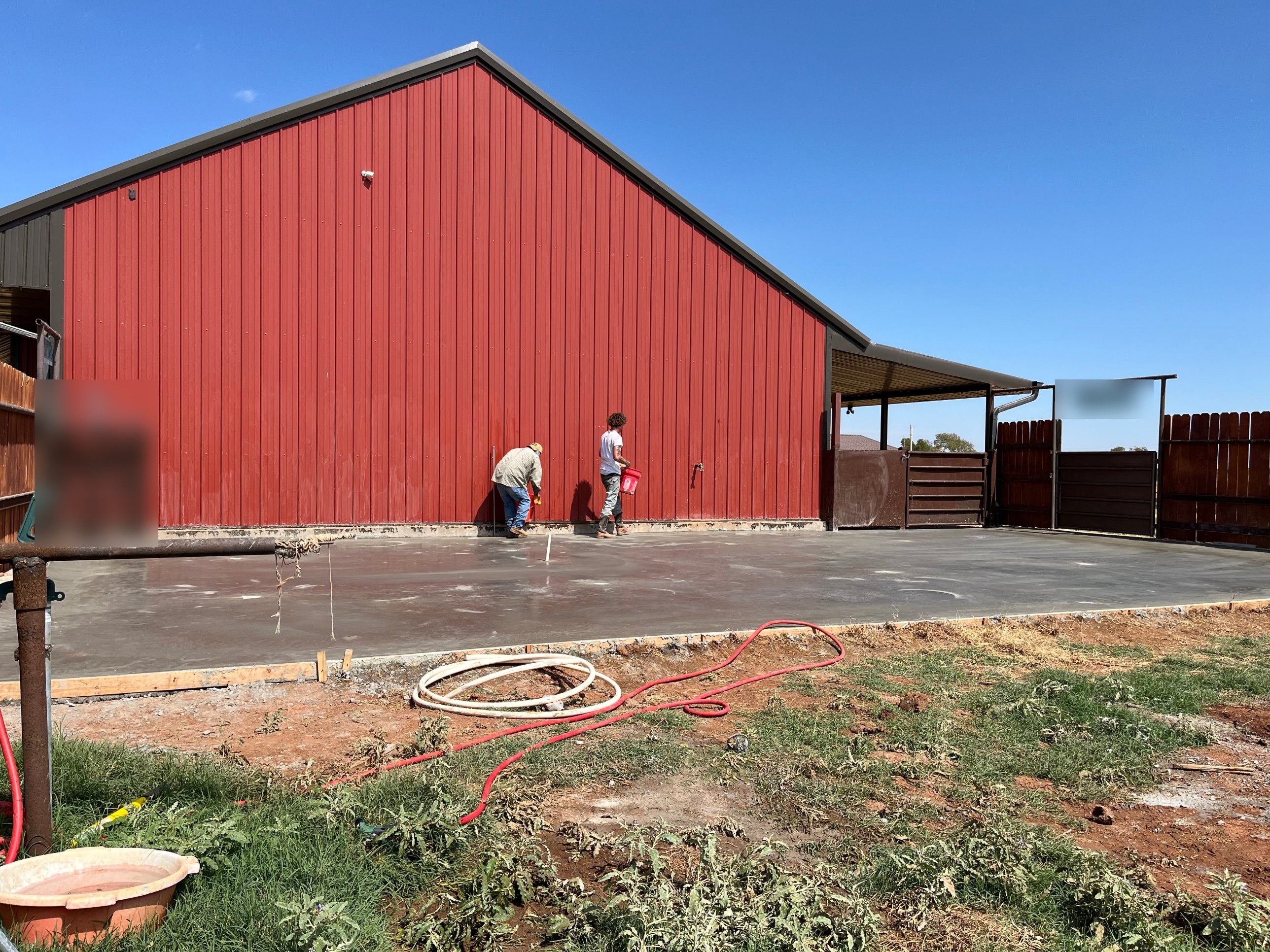 New concrete slab poured beside a red metal barn in North Texas