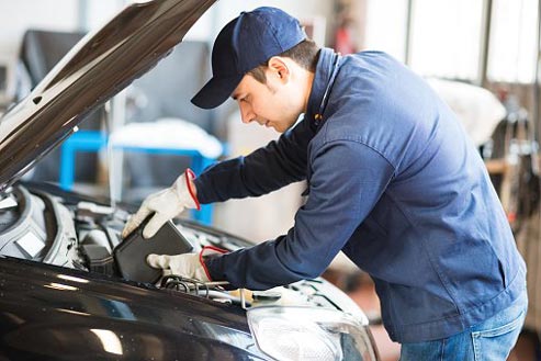 Automotive technician performing scheduled maintenance and inspection at Larry's Auto Service