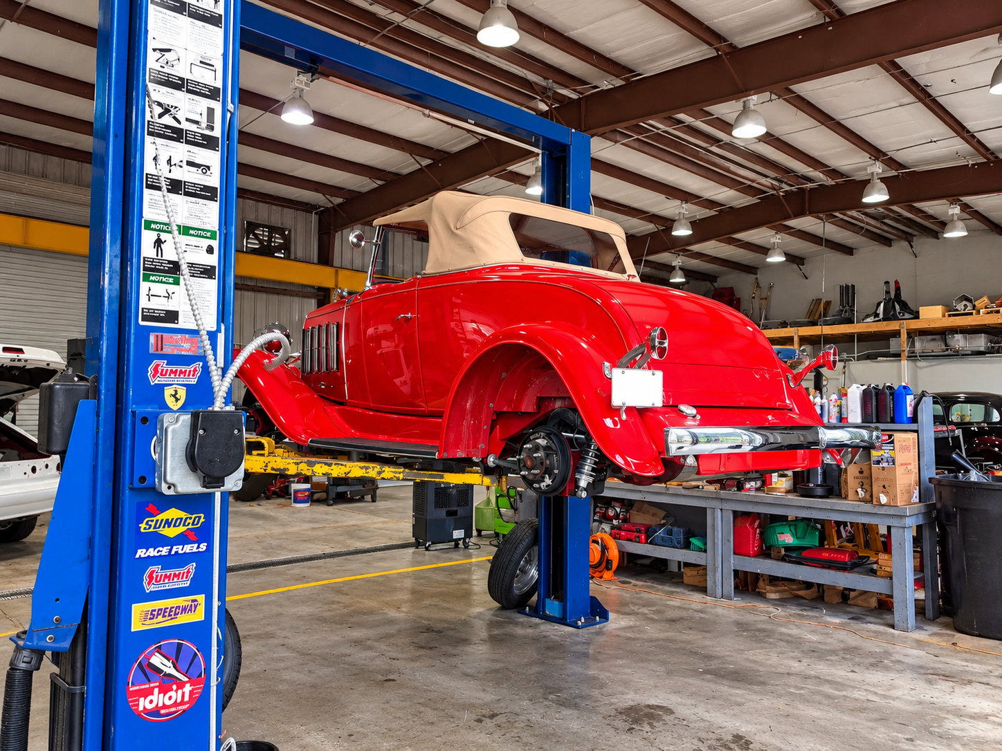 Vintage red roadster on the hydraulic service lift inside Larry's Auto Service shop bay