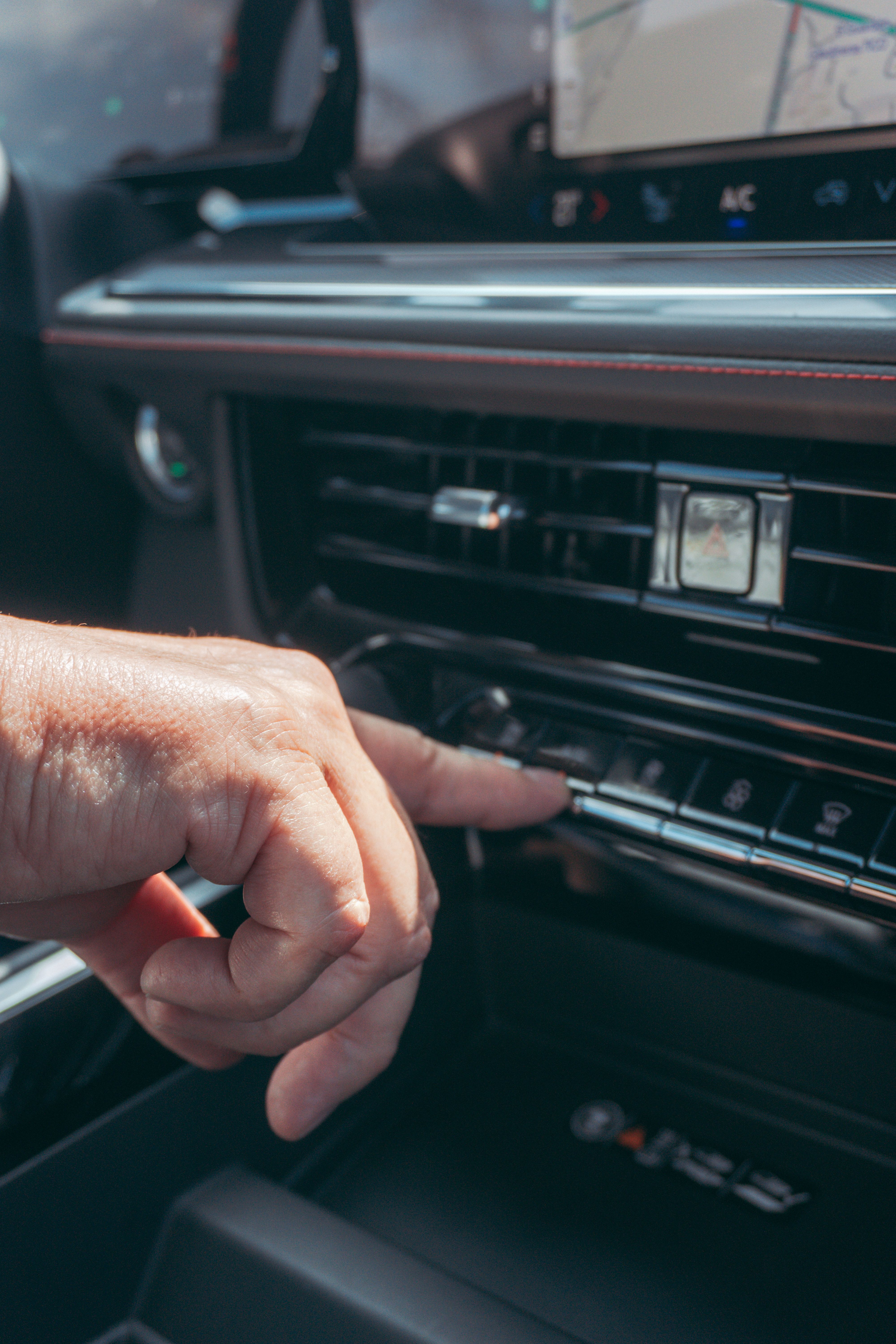 Driver adjusting vehicle air conditioning and climate controls on dashboard