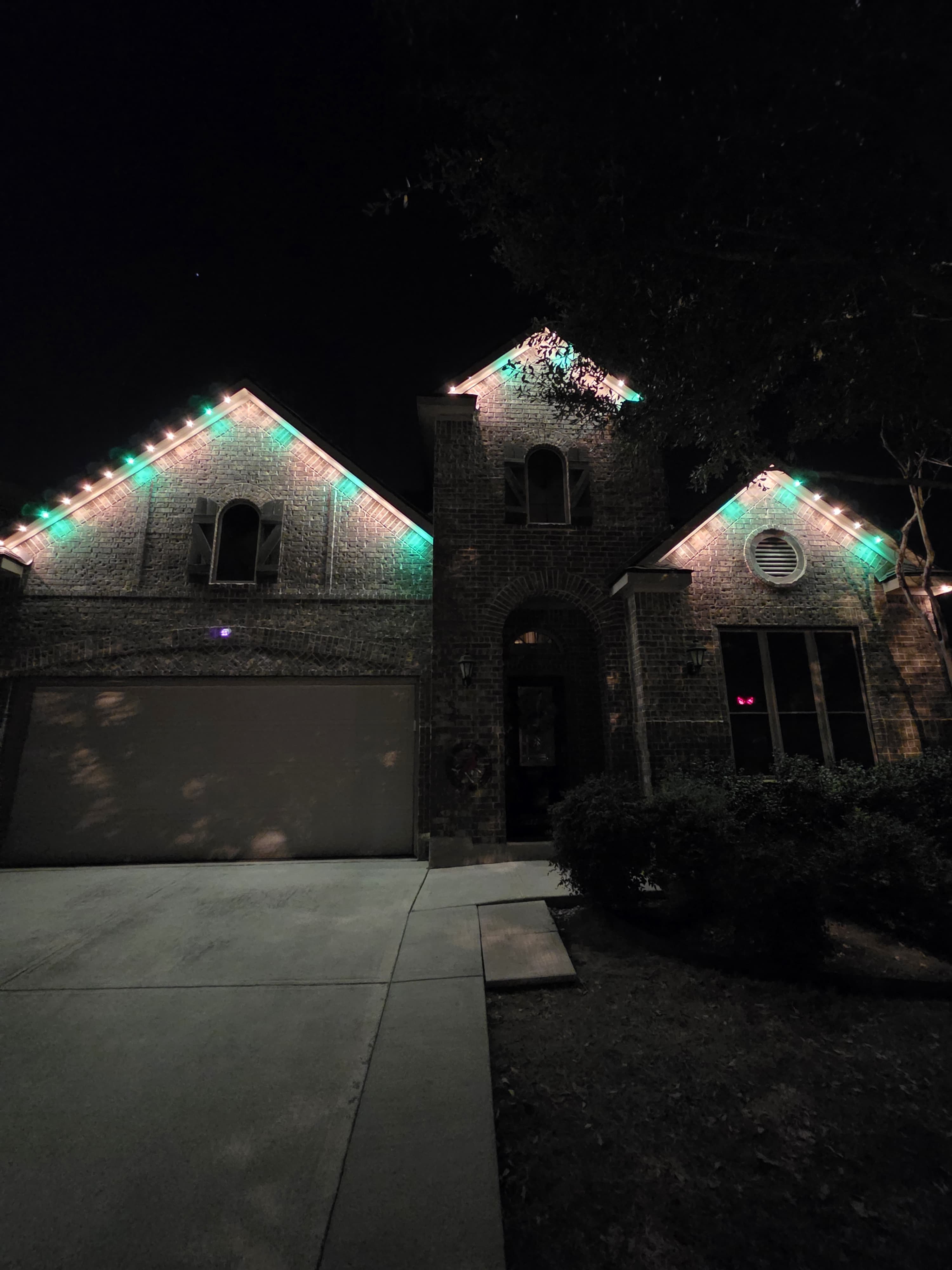 Close view of precision permanent lights following stone home gables and roof peaks