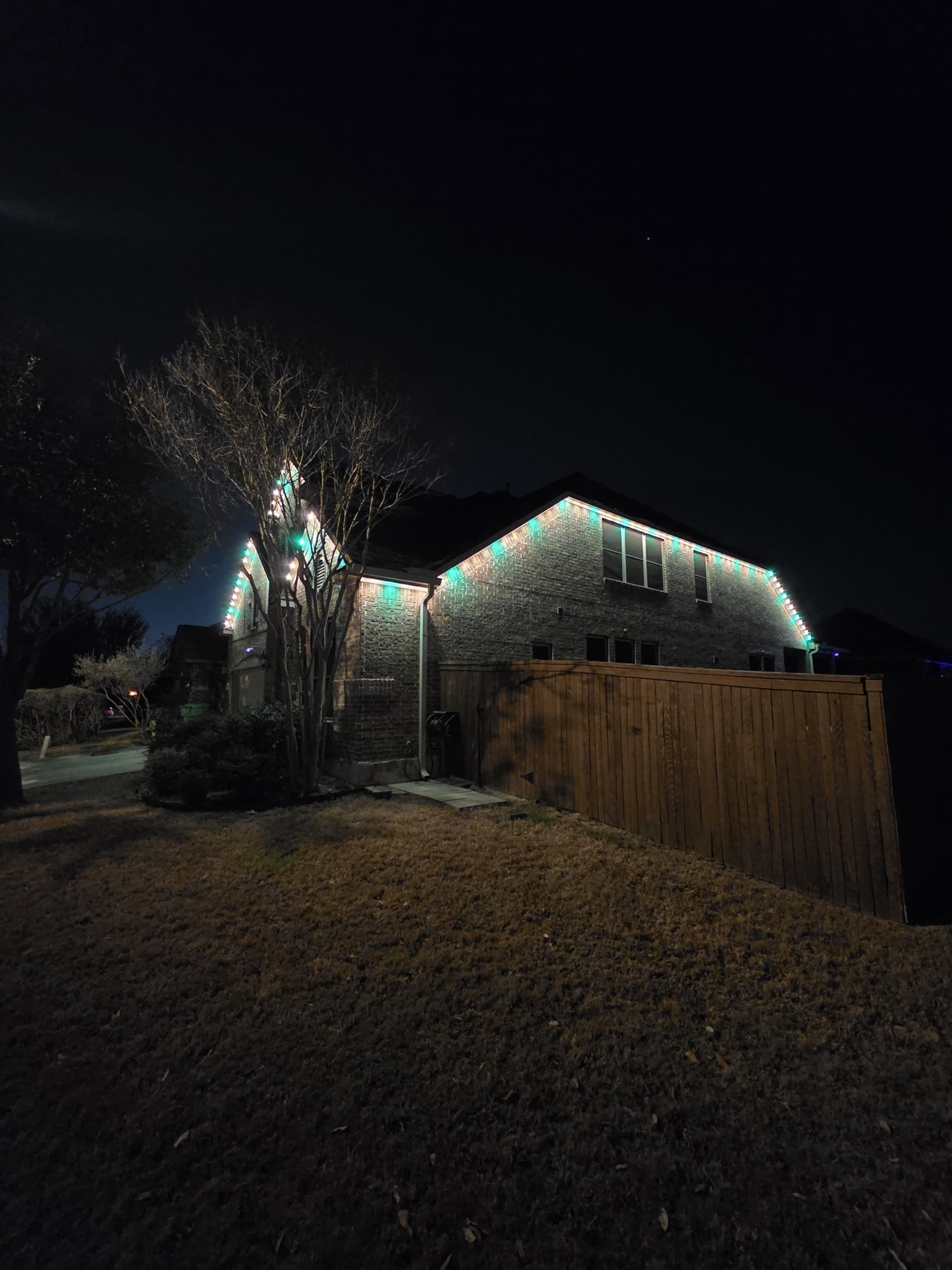 Two-story Texas home roofline illuminated with festive holiday LED lighting installed by Roofio