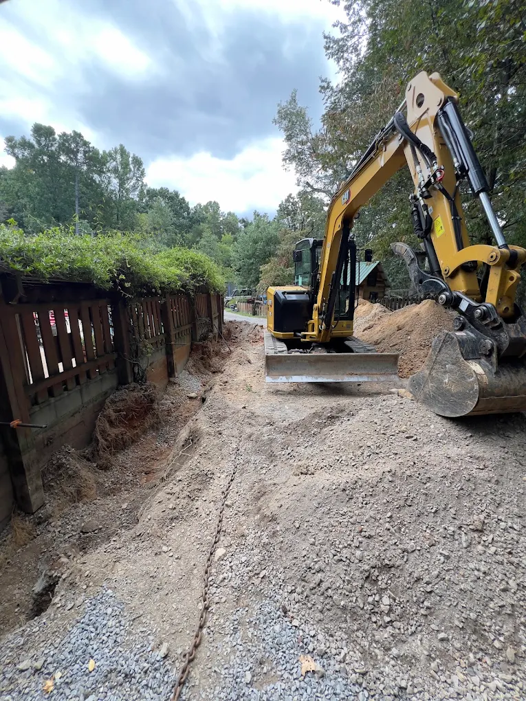 Excavator working beside a defined trench.