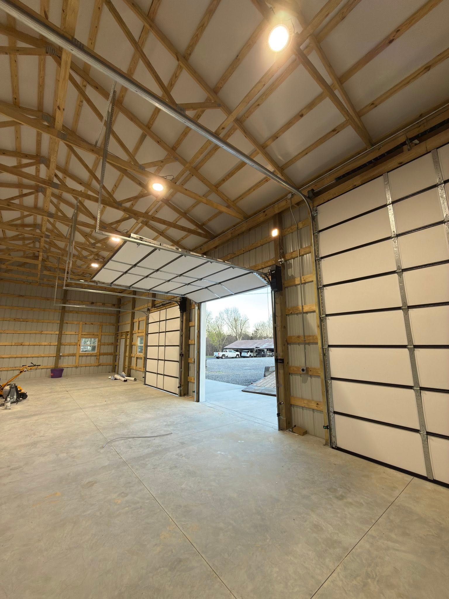 Commercial post-frame facility with commercial electrical wiring, lighting, and roll-up door opener installations.
