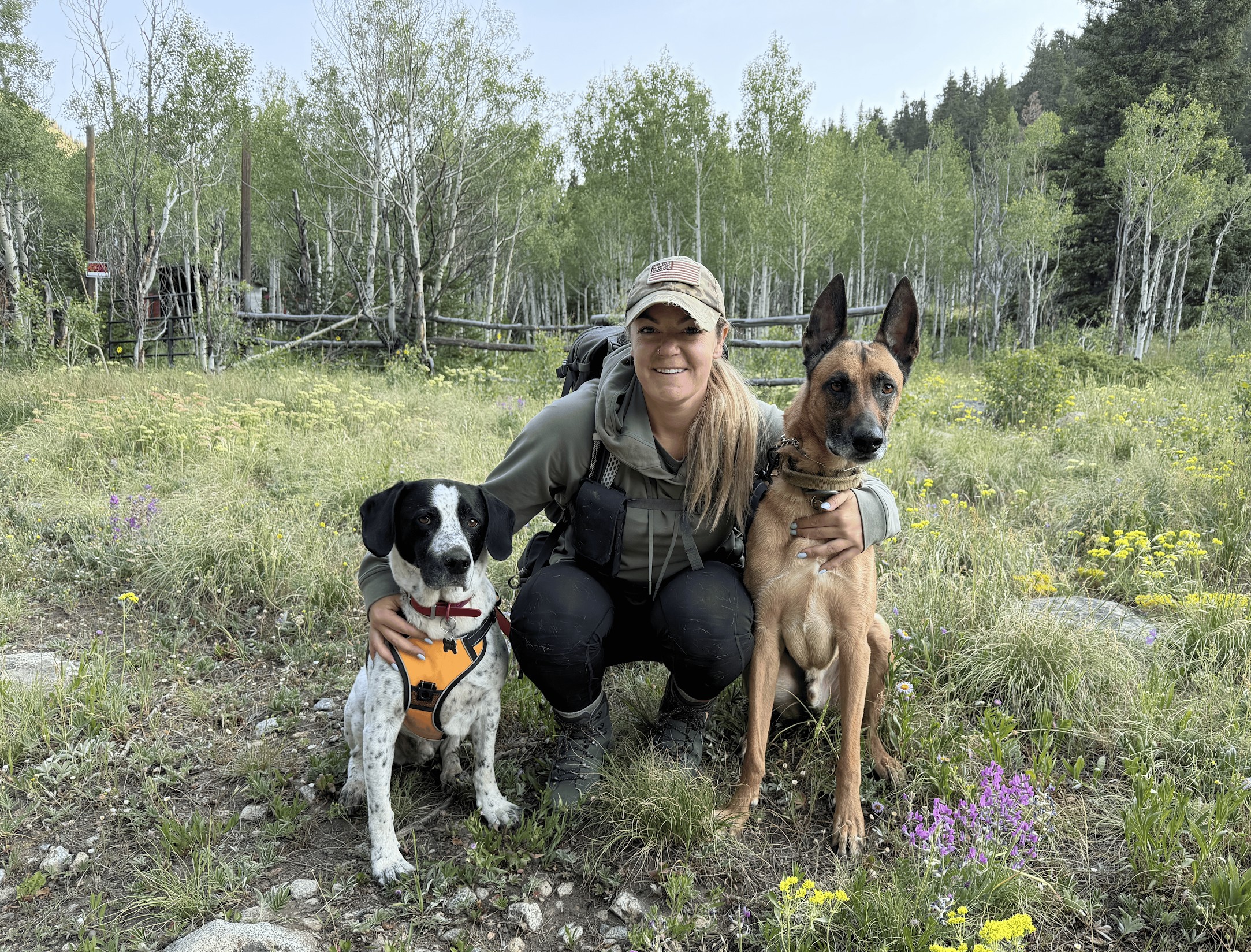 Riley smiling outdoors in the mountains with Niko and their dog companion
