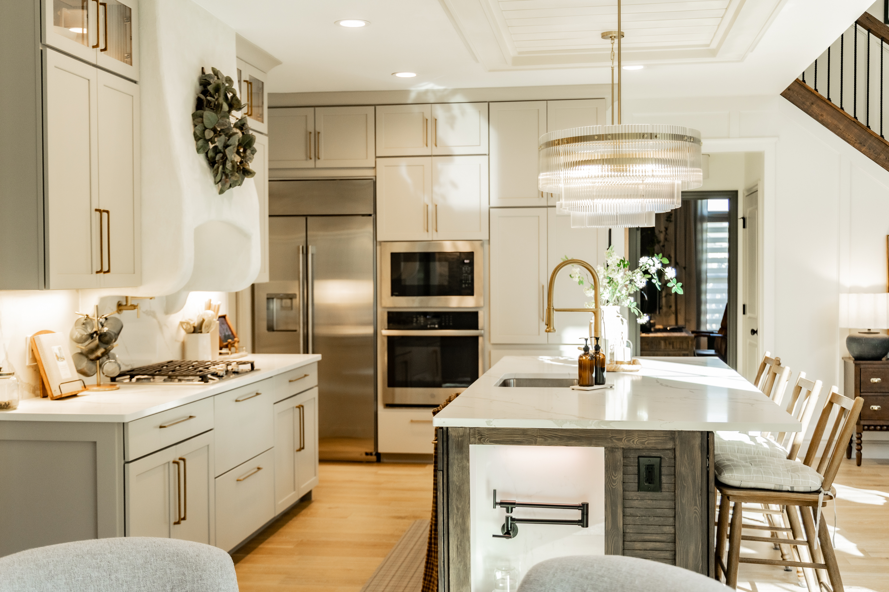 Wide angle view of luxury kitchen remodel in Wentzville MO featuring large center island with seating, brass pendant lights, custom cabinetry, and open dining area