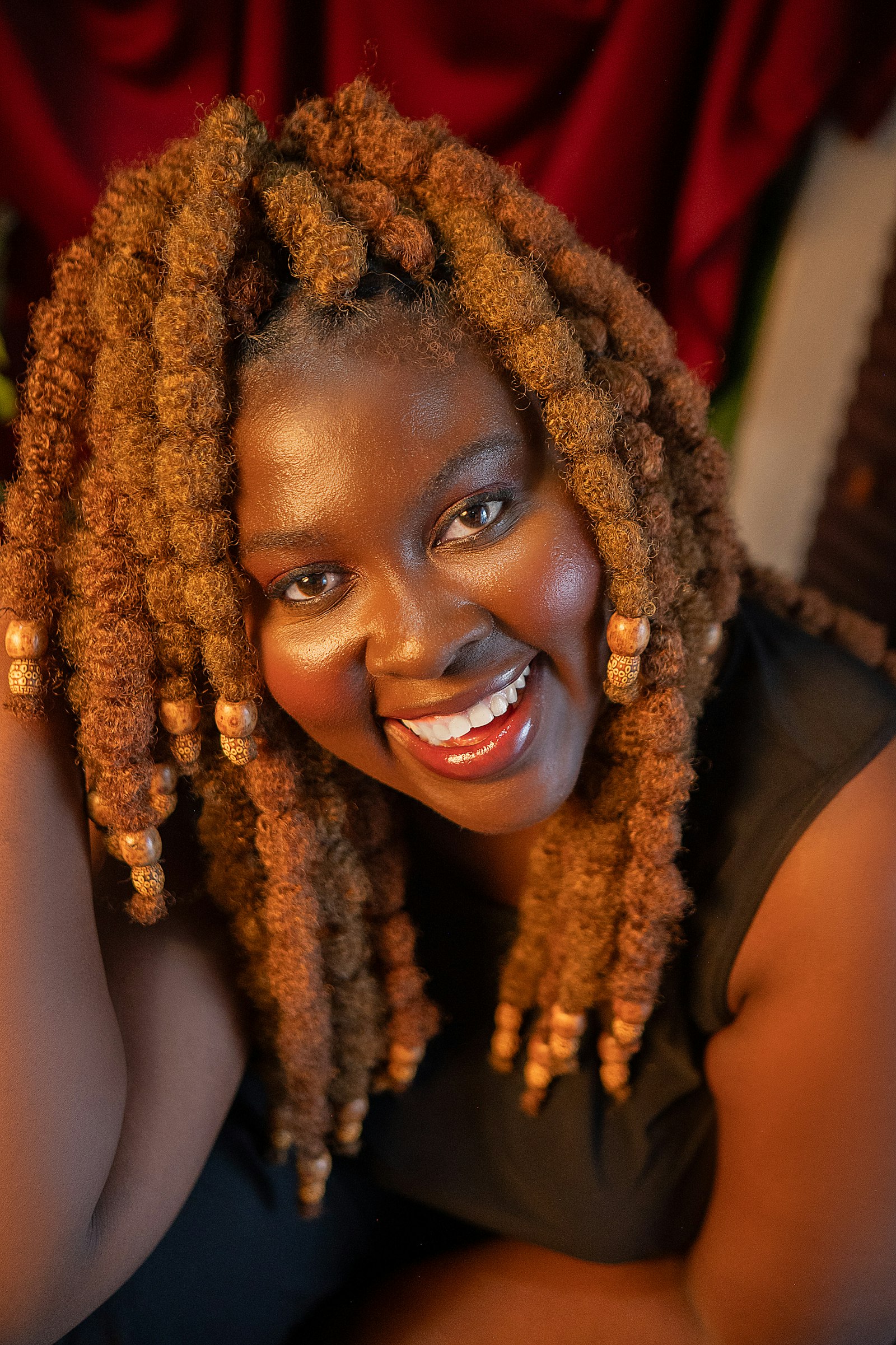 A smiling woman with healthy, moisturised locs and beads, illustrating proper between-visit loc care at La Salon in Pickering