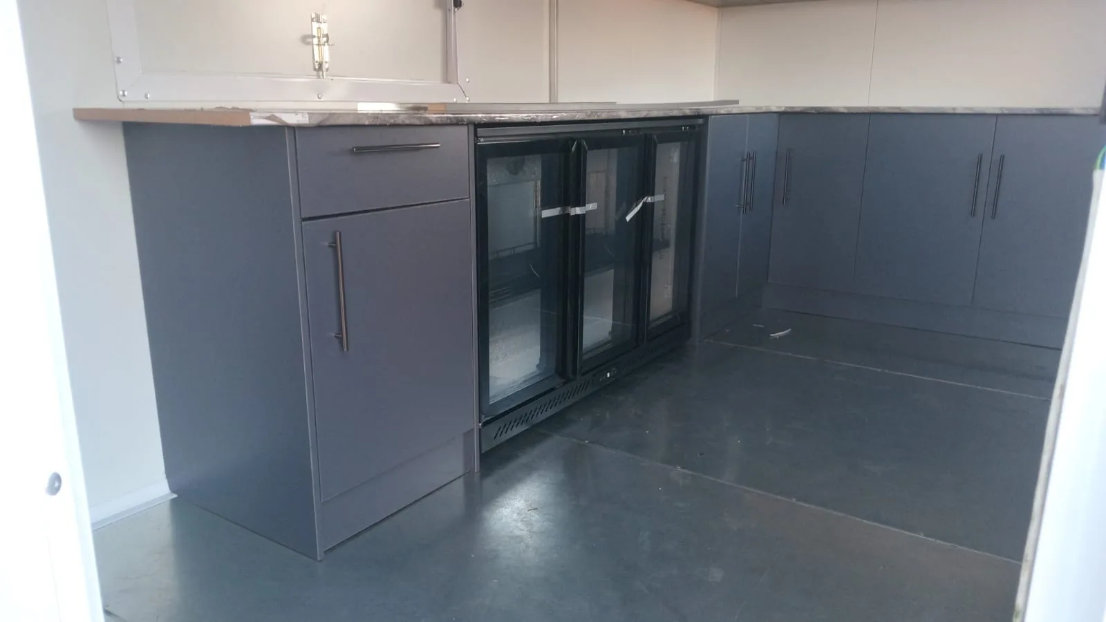 Glass-door bar fridge and cupboards inside Nom Bango