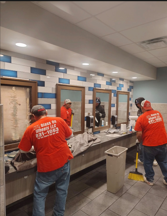Glass on Wheels crew in company shirts installing framed commercial vanity mirrors in restroom facility