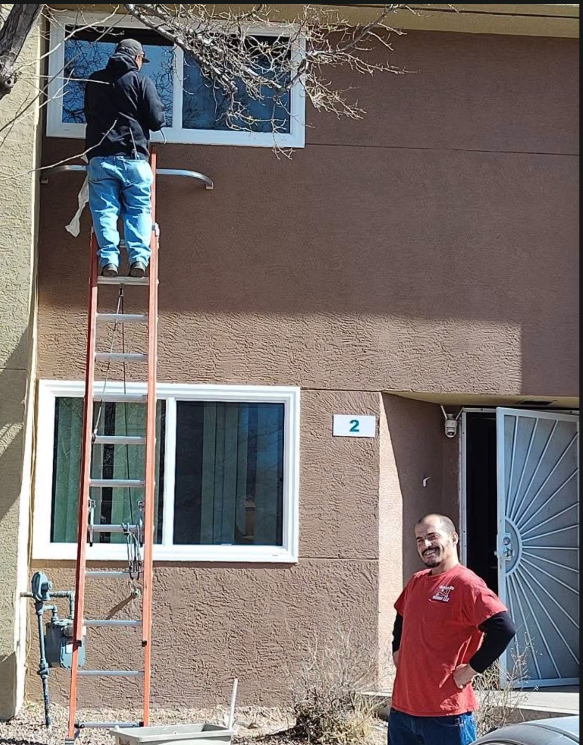 Glass on Wheels technician on extension ladder servicing second-story residential window