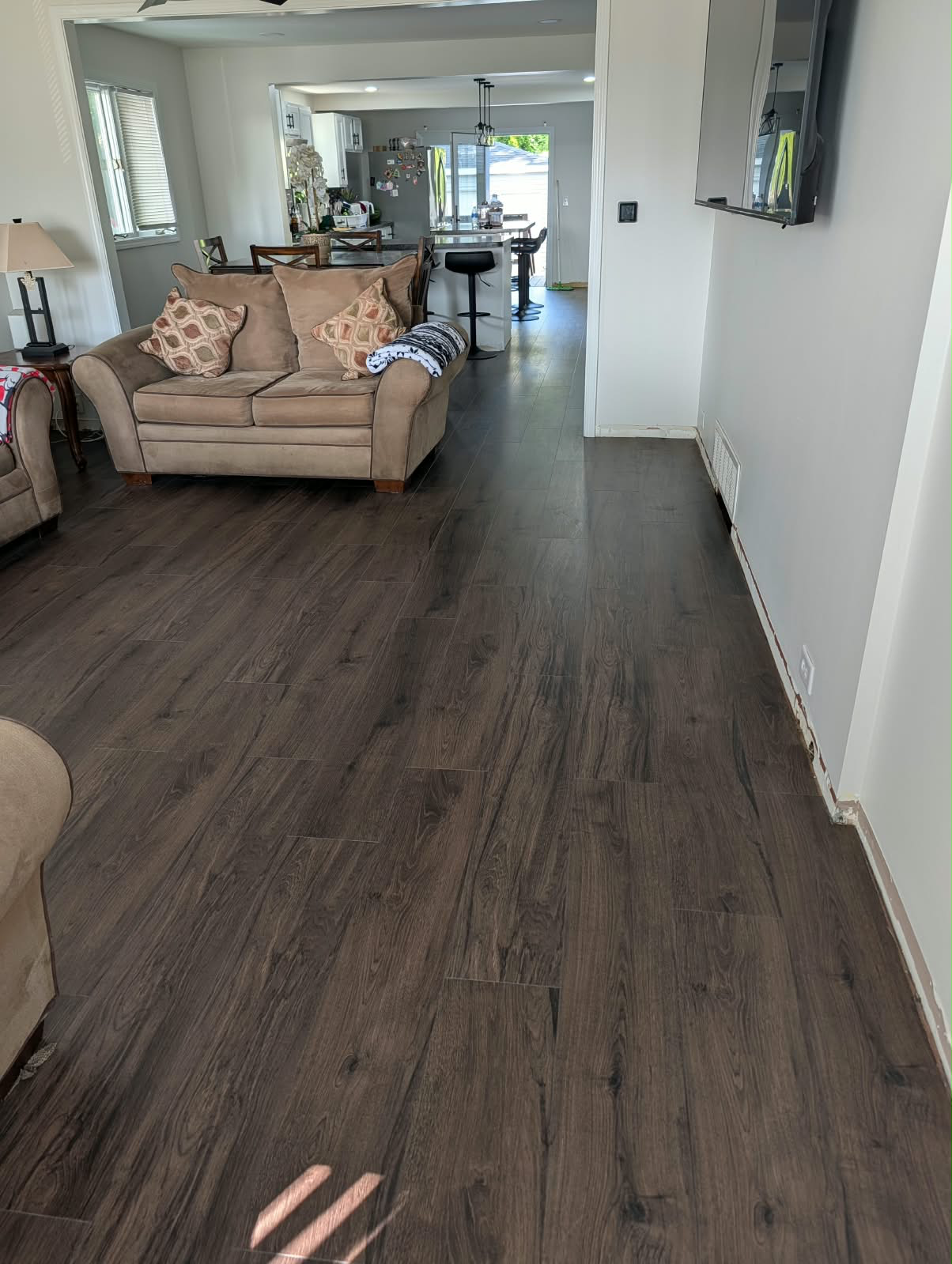 Seamless dark walnut luxury vinyl plank flooring through living room and kitchen