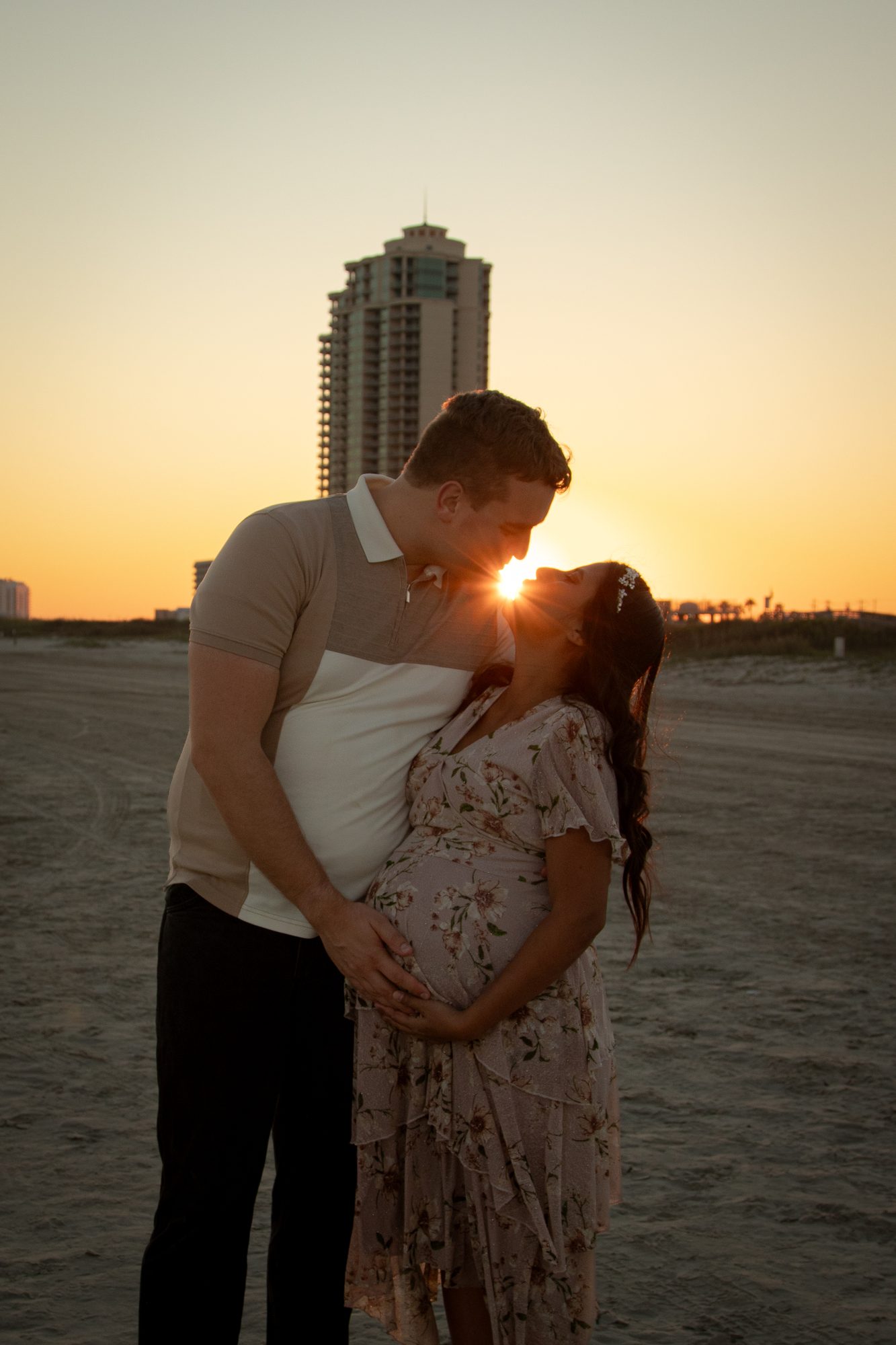 Couple kissing at sunset on the beach with the sun between them