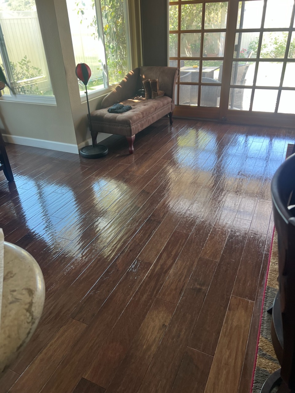 Gleaming sunlit polished hardwood living floor cleaned by Julia's House Cleaning