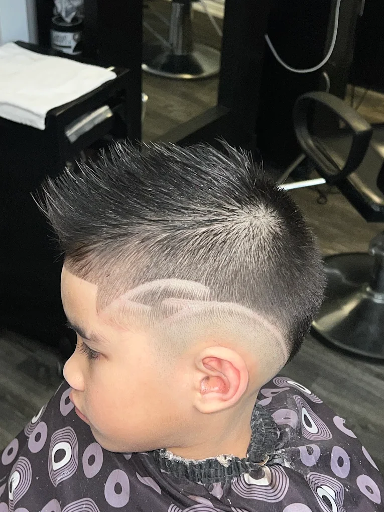 Young boy side profile low skin fade with custom dual curved razor wave design and textured spiky mohawk top at Image Barber Studio