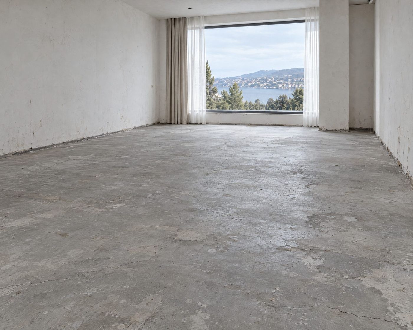 Sala antes: piso de concreto desgastado, vacío con vista al lago