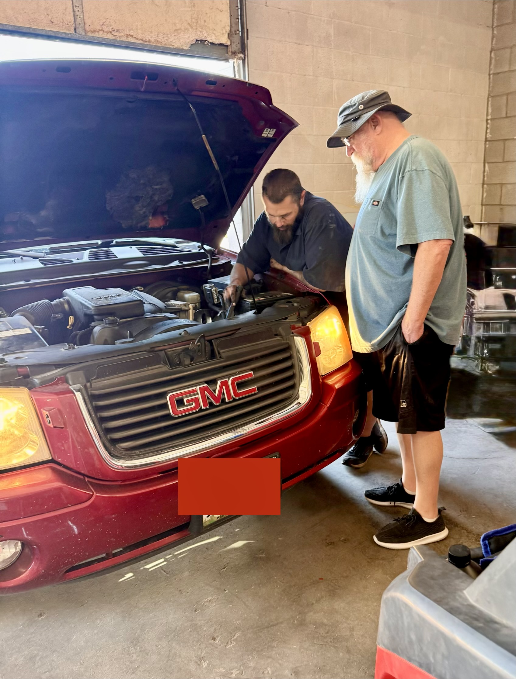 Brandon, The Rusty Ratchet mechanic in Fallon, NV, explaining diagnostic results to a customer beside a vehicle