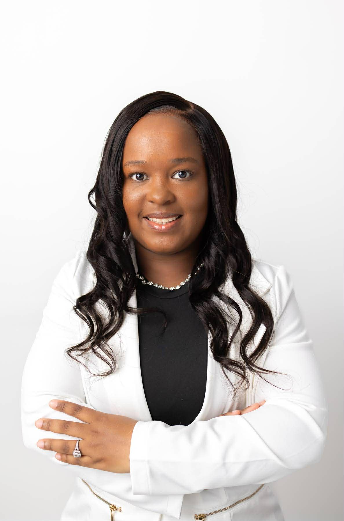 Headshot of Tia Windon smiling, wearing a white blazer over a black top