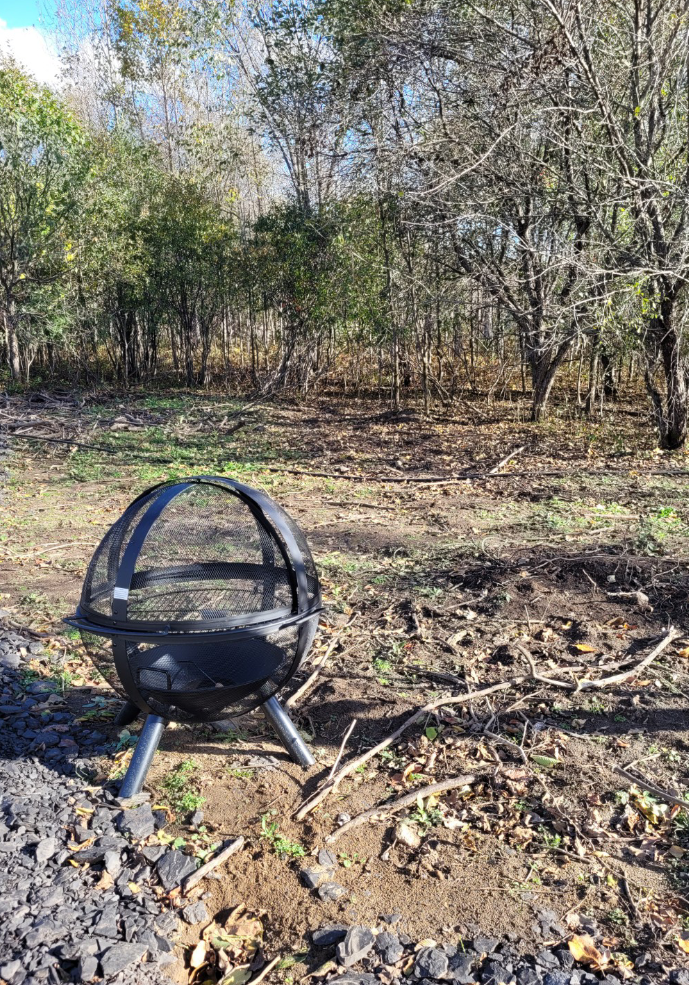 Enclosed fire pit bowl in woodland clearing at Findlay Creek Farmstead