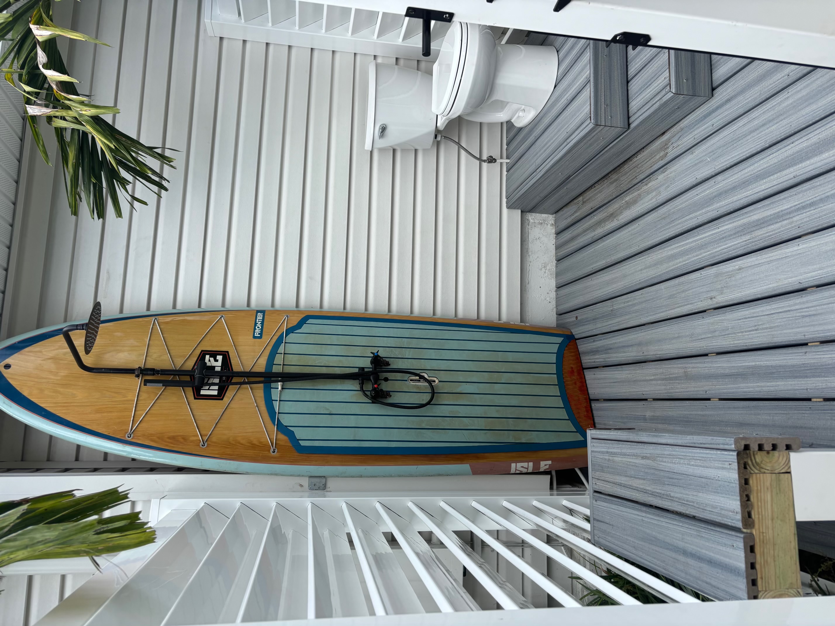 Wide interior view of the outdoor shower and bath enclosure featuring composite decking steps, surfboard shower, and white vinyl louvers