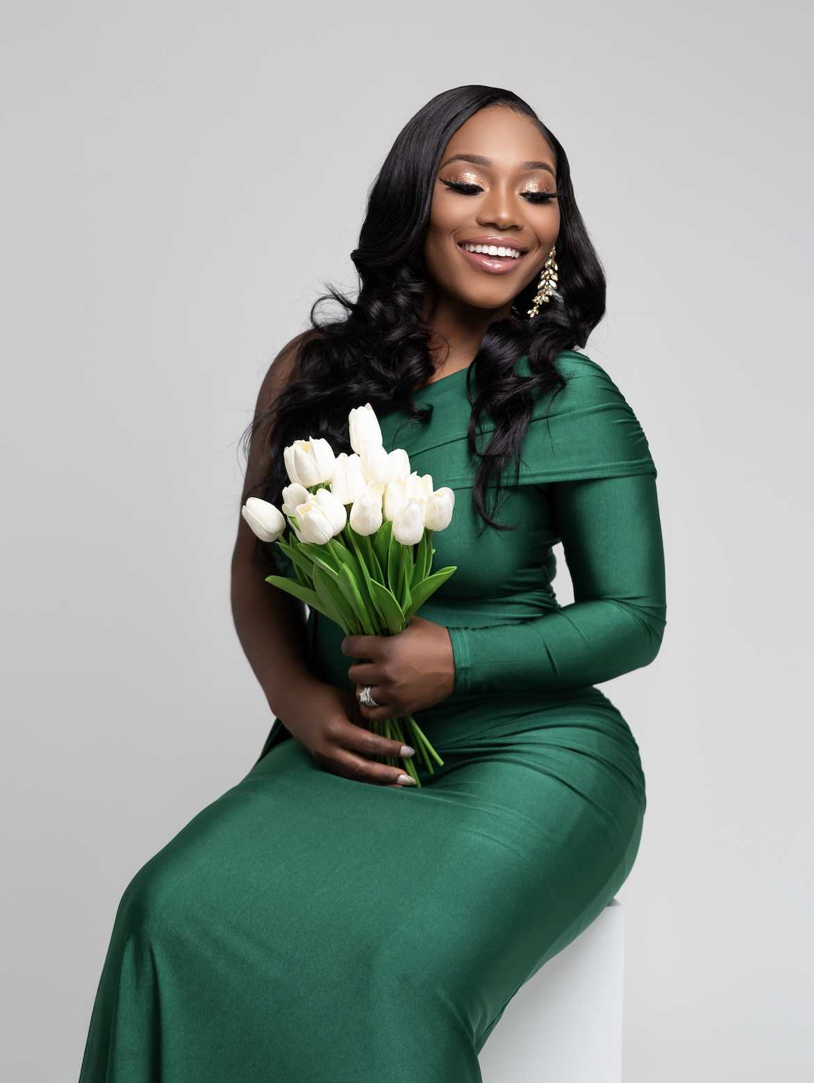 Coach Roxy smiling with white tulips in an emerald green gown