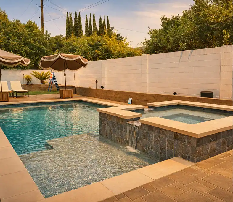 Custom concrete and paver pool deck with raised spa and spillway