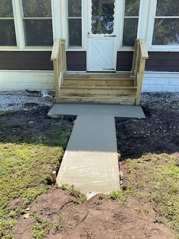 Freshly poured concrete entryway walkway leading up to front porch steps