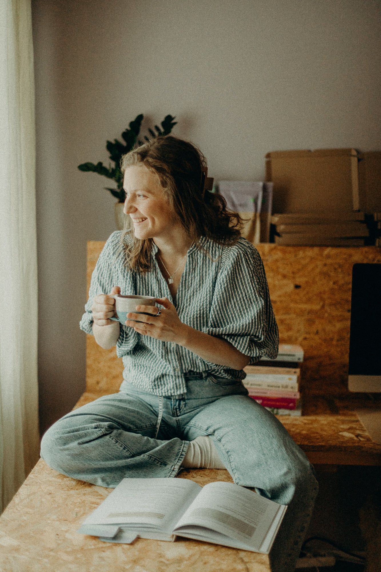 Rebecka sitter med en kopp te och en öppen bok