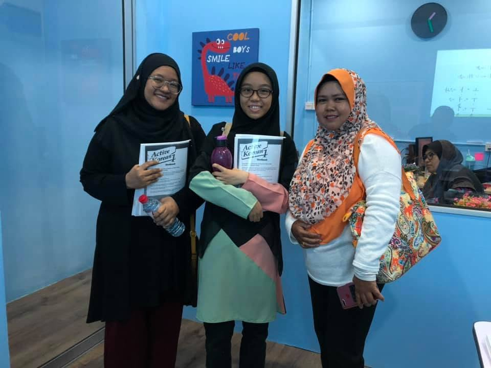 Pelajar ceria memegang buku modul pembelajaran Active Korean 1 di bilik kelas Pusat Bahasa Kuala Selangor